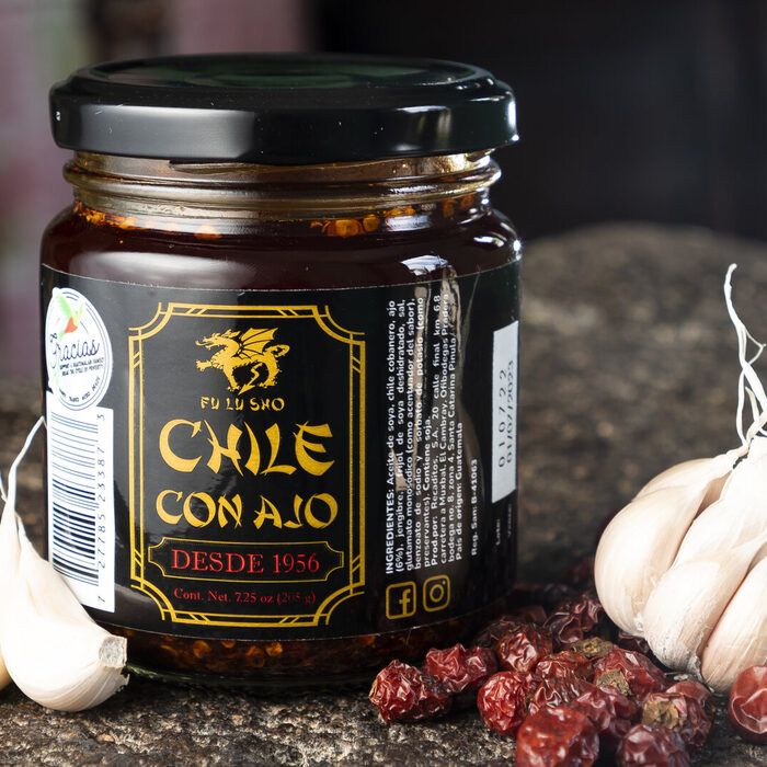Frasco de Chile con Ajo Fu Lu Sho entre chiles secos y cabezas de ajo